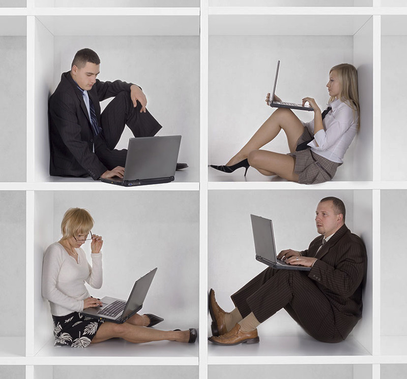 Женщина в деловом костюме с галстуком, сидит на стуле с ноутбуком.