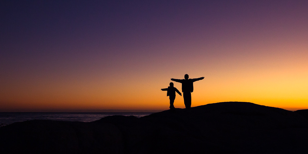 Силуэт взрослого мужчины на фоне заката в природе и небе.