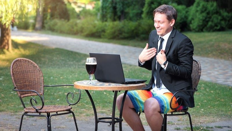 Человек сидит на улице с ноутбуком в пальто - SEO оптимизированный текст для изображения.