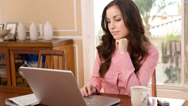 Исполнитель с ноутбуком, выпивающий кофе, концентрируется на работе в офисе.