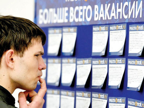 Человек читает текст на голове афиши с лицом на рекламном постере.